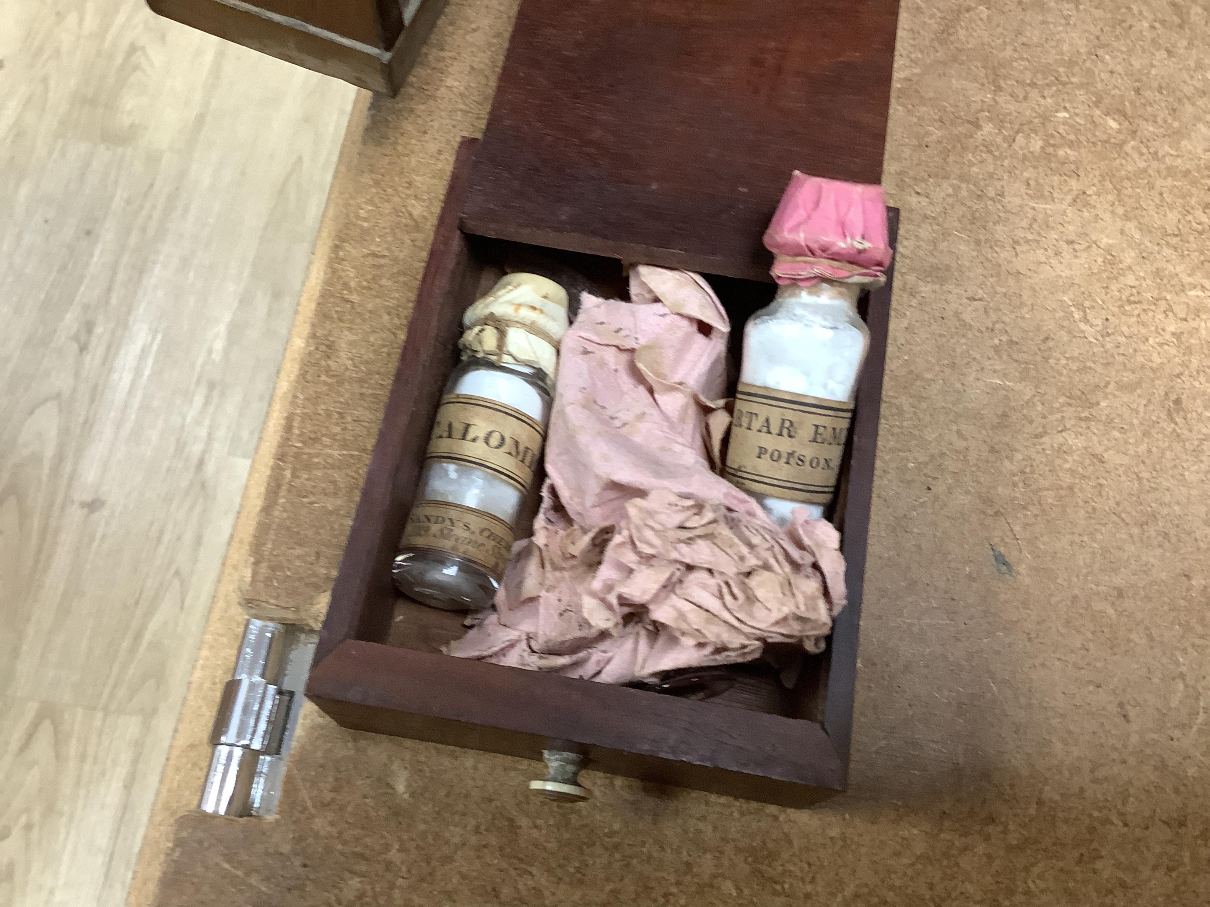 A 19th century mahogany apothecary cabinet, containing 20 bottles of various medicinal compounds and poisons, some sealed, all with paper labels, mainly for ‘C. Woollven, Operative & Dispensing Chemist, 108, High Street,